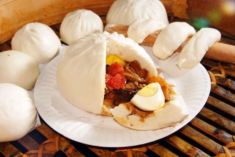 Steamed jumbo pau, opened to show egg and braised filling