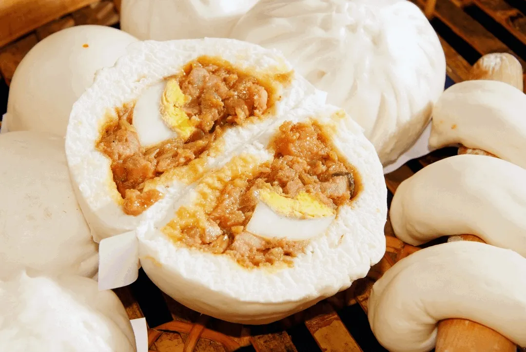 A big pau cut open to show minced meat and a slice of egg