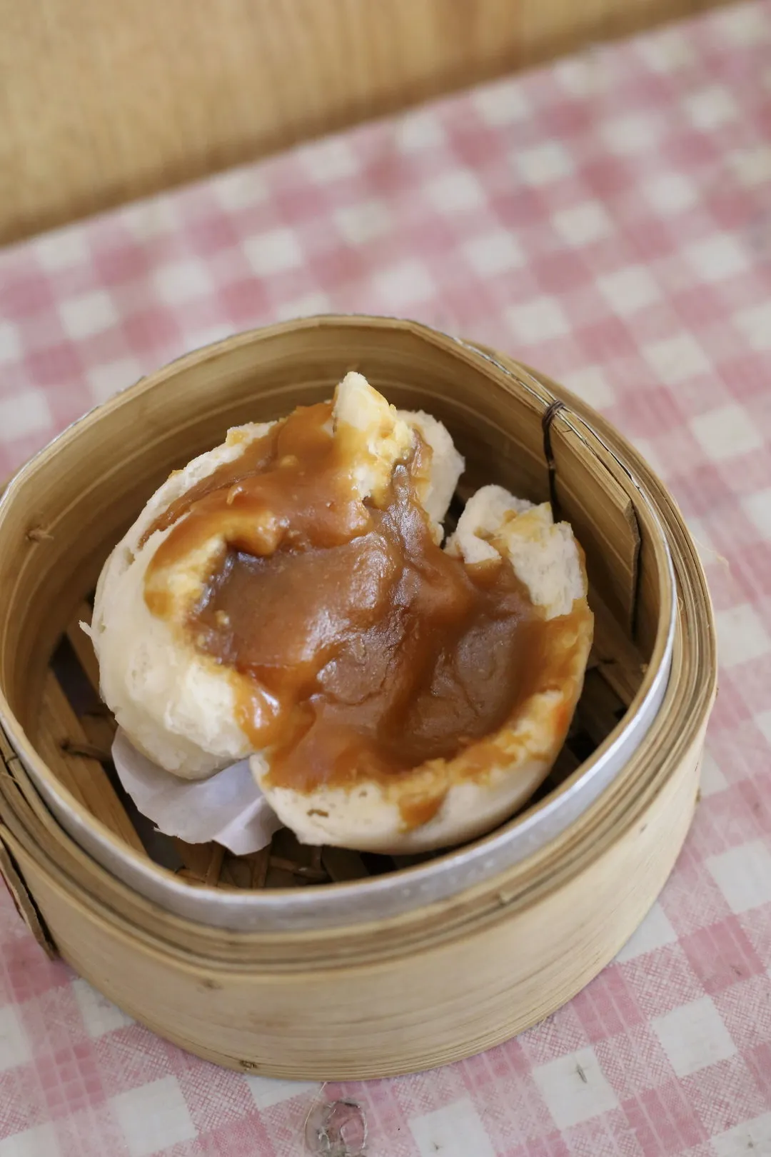 A lotus paste pau broken open in a bamboo steamer