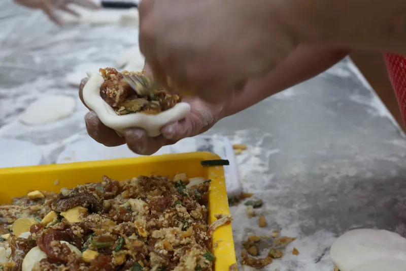 Spooning savoury filling into a round of pau dough