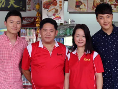 Four people at the shop, two of them in red Kung Fu JB Pau polos