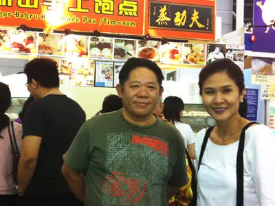 A man in a green shirt and a woman in white at a Kung Fu JB Pau stall