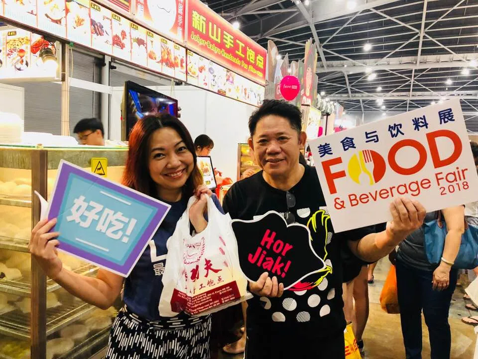 Two people holding signs at the Food and Beverage Fair 2018