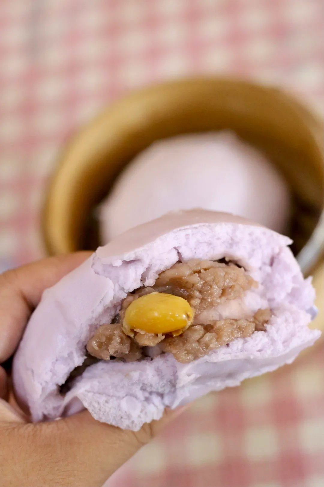 A purple yam pau torn open to show yam paste and a gingko nut